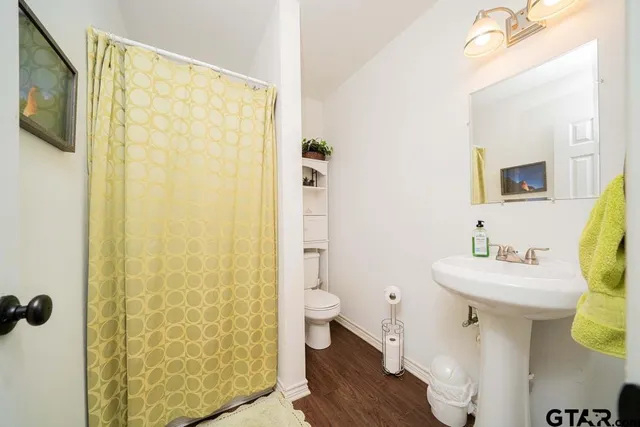 a bathroom with a sink a toilet a mirror and shower