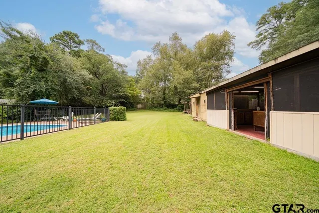 a view of a house with pool and trees in the background