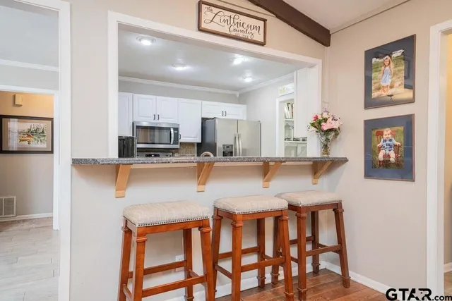 a kitchen with stainless steel appliances granite countertop a dining table chairs refrigerator and sink