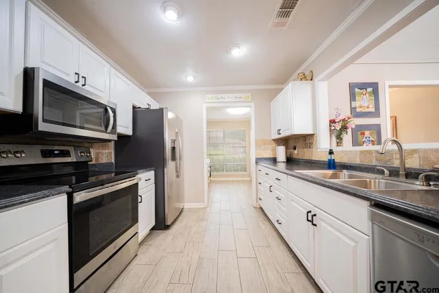 a large kitchen with stainless steel appliances granite countertop a stove a sink and a microwave