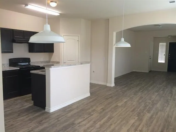 a kitchen with granite countertop a stove and a wooden floor