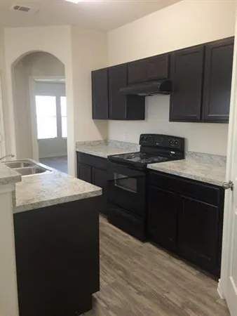 a kitchen with granite countertop wood cabinets stainless steel appliances and a sink
