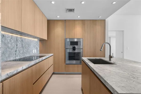 a kitchen with kitchen island granite countertop a sink and refrigerator