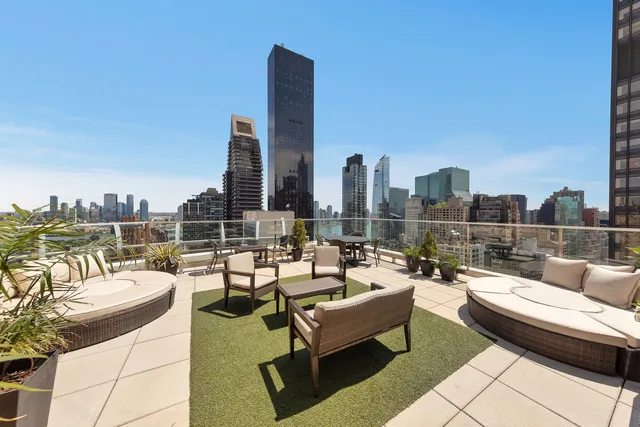 a roof deck with couches and potted plants with sky view