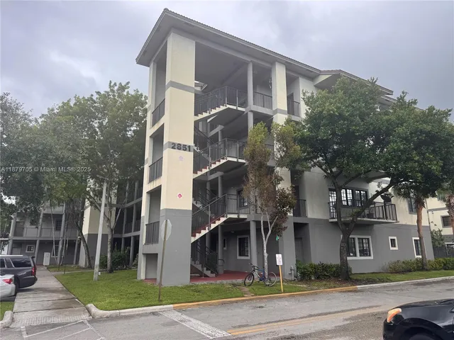 a front view of a building with a garden and plants