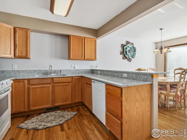 a kitchen with stainless steel appliances granite countertop wooden cabinets a sink and dishwasher with wooden floor