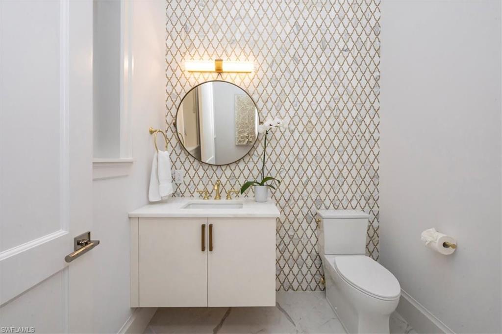 493 8th Avenue South Naples, FL 34102 - Photo 23 of 40 a bathroom with a toilet a sink and mirror