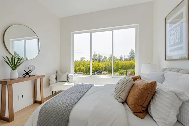 a bedroom with a bed a mirror and a large window