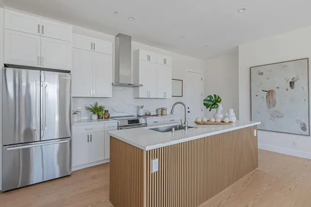 a kitchen with stainless steel appliances granite countertop a refrigerator a sink a stove a dining table and chairs