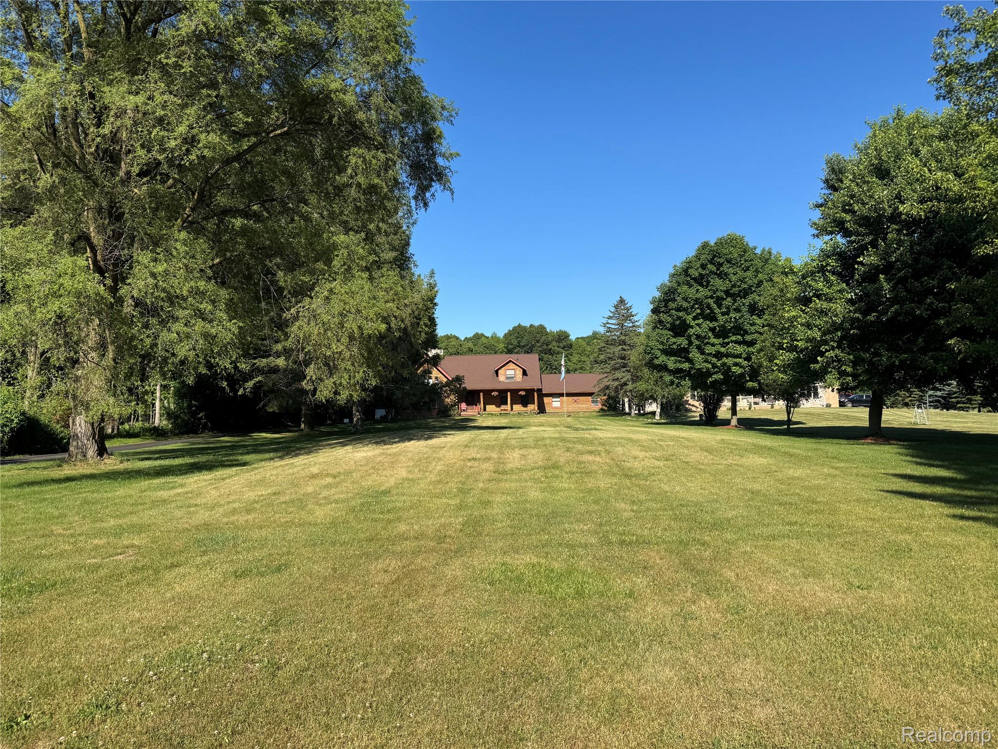 16501 Hannan Road Romulus, MI 48174 - Photo 2 of 20 Expansive front lawn featuring mature trees and a distant dwelling with a gabled roof and covered entry