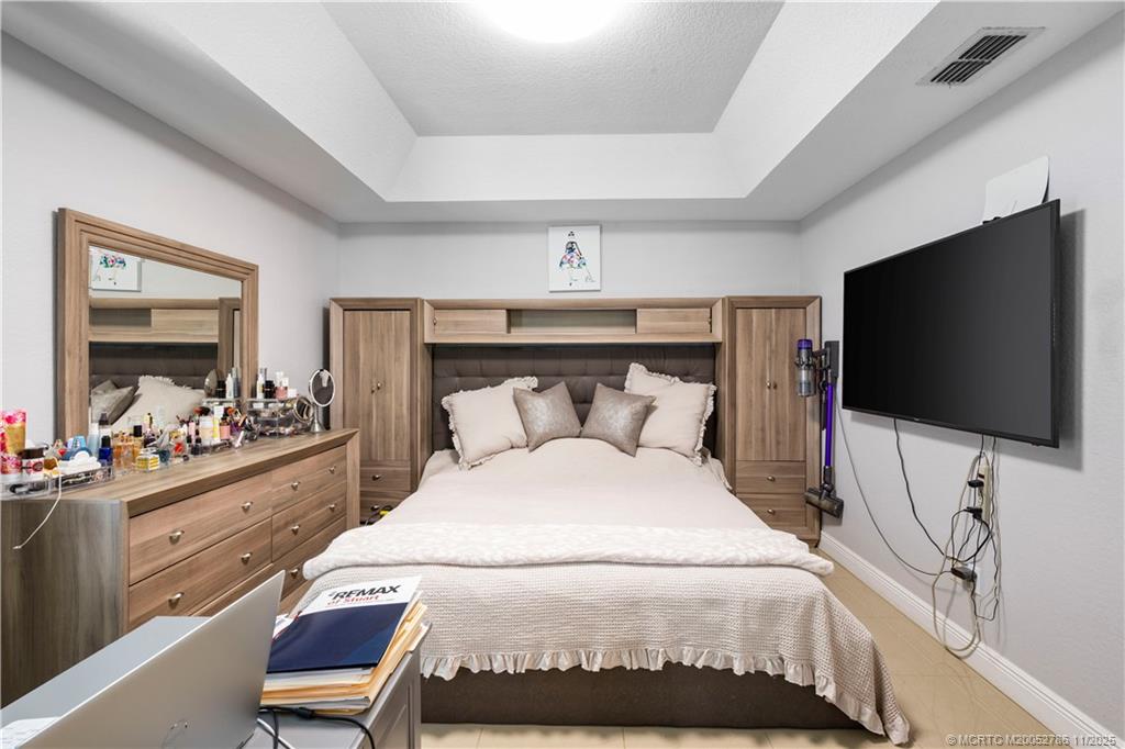 3785 Southeast Middle Street Stuart, FL 34997 - Photo 16 of 31 a bedroom with a bed and a flat tv screen on wall