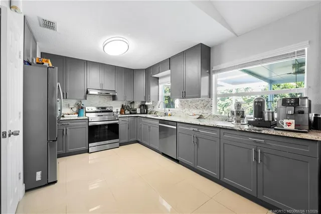 a kitchen with stainless steel appliances kitchen island granite countertop a refrigerator and sink