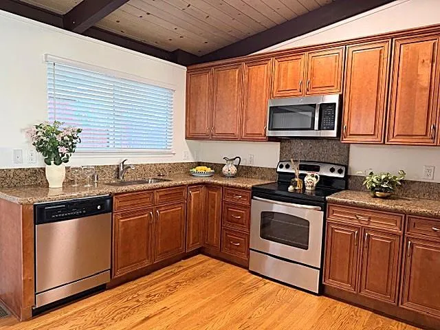 a kitchen with stainless steel appliances granite countertop a sink a stove and cabinets
