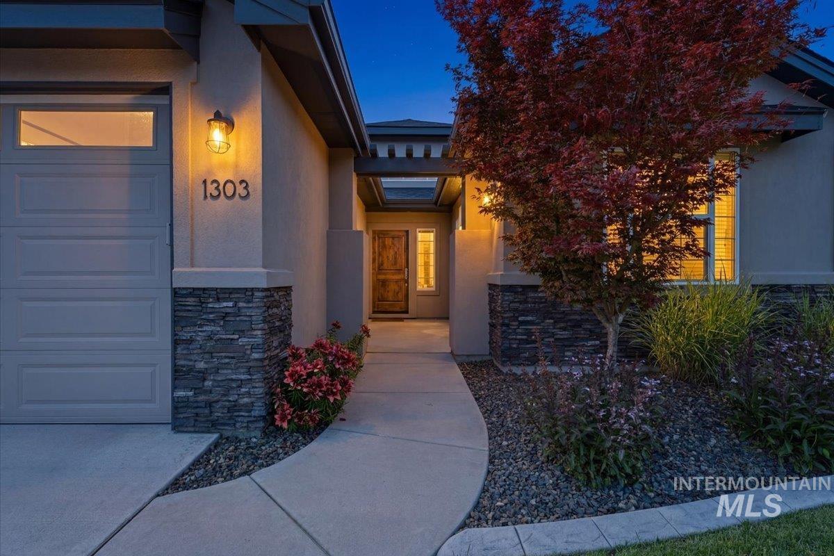 1303 West Brando Street Meridian, ID 83646 - Photo 3 of 49 Contemporary stucco exterior with stone accents, featuring a wood-panel front door and a concrete walkway
