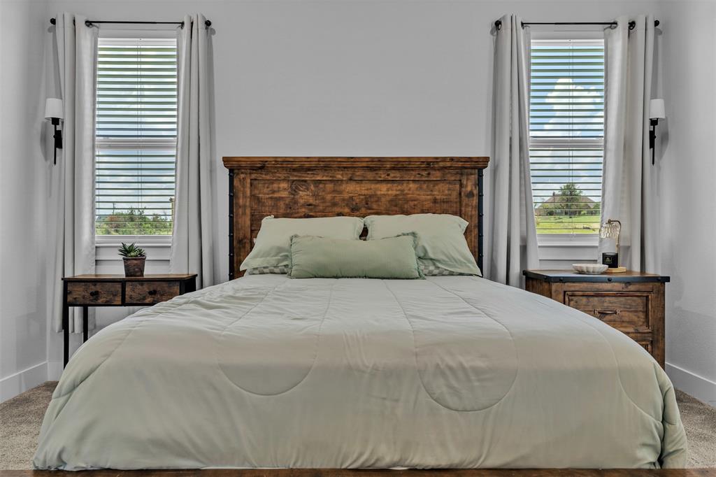 2004 Willy Dilly Road Springtown, TX 76082 - Photo 25 of 40 Bedroom featuring a wood-finish headboard, twin windows with blinds and drapery, and wall-mounted sconces