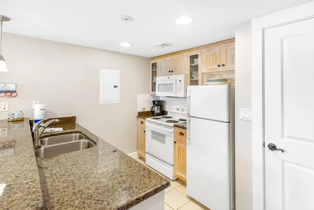 a kitchen that has a refrigerator a stove a sink and a dining table with wooden floor