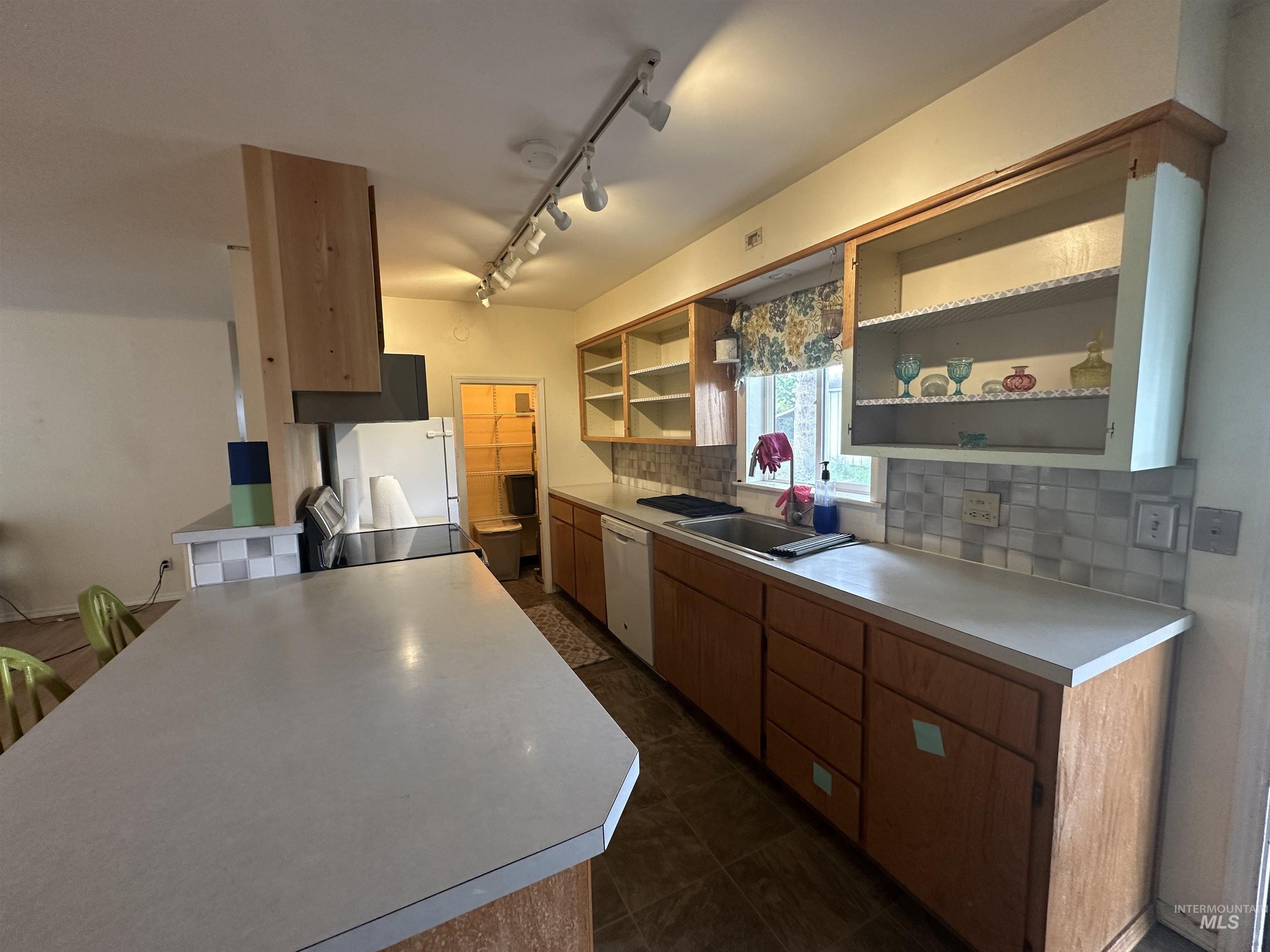 630 Preston Avenue, Unit C Lewiston, ID 83501 - Photo 6 of 10 Spacious kitchen featuring an extended counter bar, wood-finish cabinetry, a ceramic tile backsplash, and track lighting