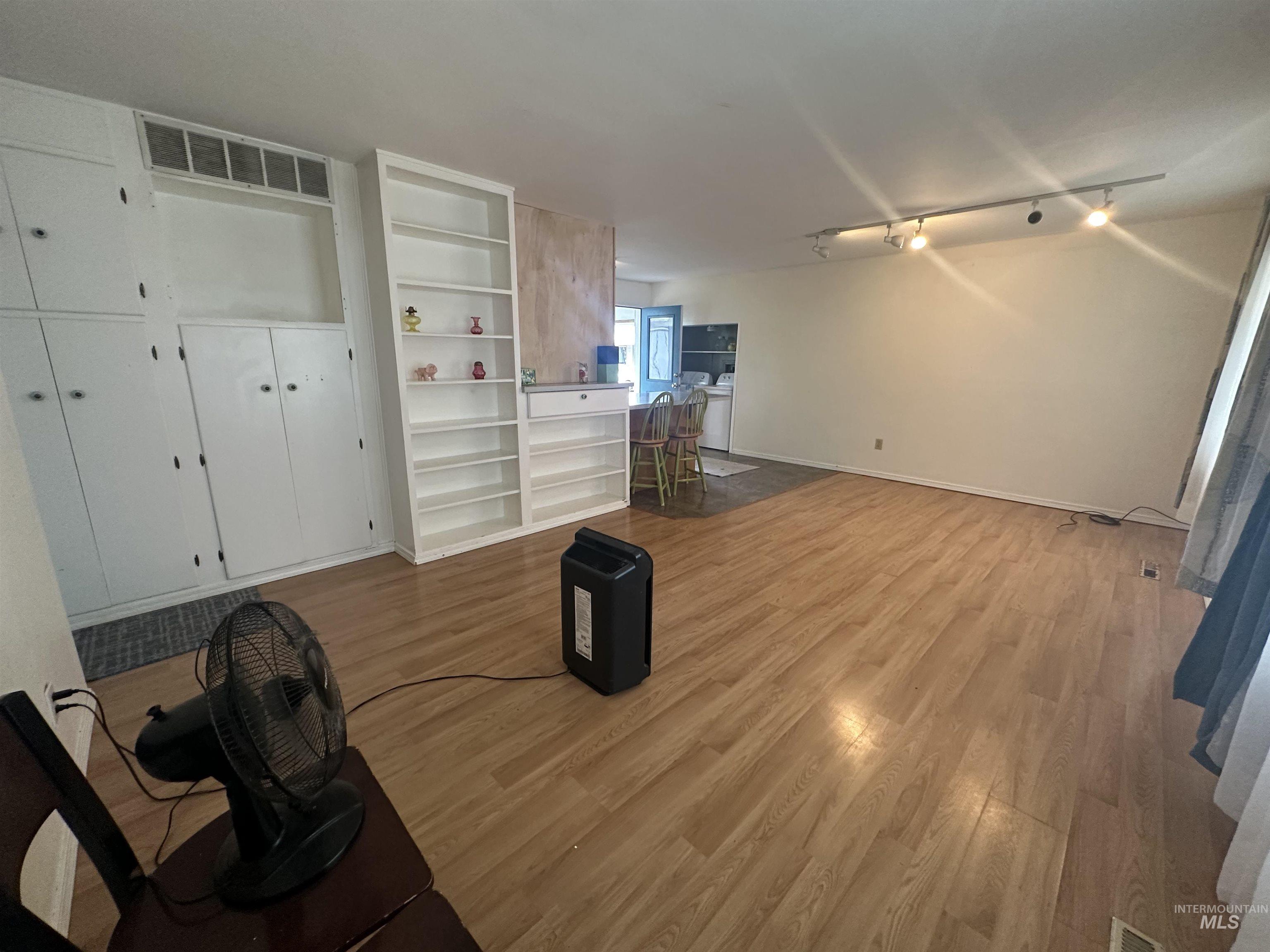 630 Preston Avenue, Unit C Lewiston, ID 83501 - Photo 7 of 10 Spacious living area featuring wood-finish flooring, track lighting, and built-in white cabinetry with integrated shelving