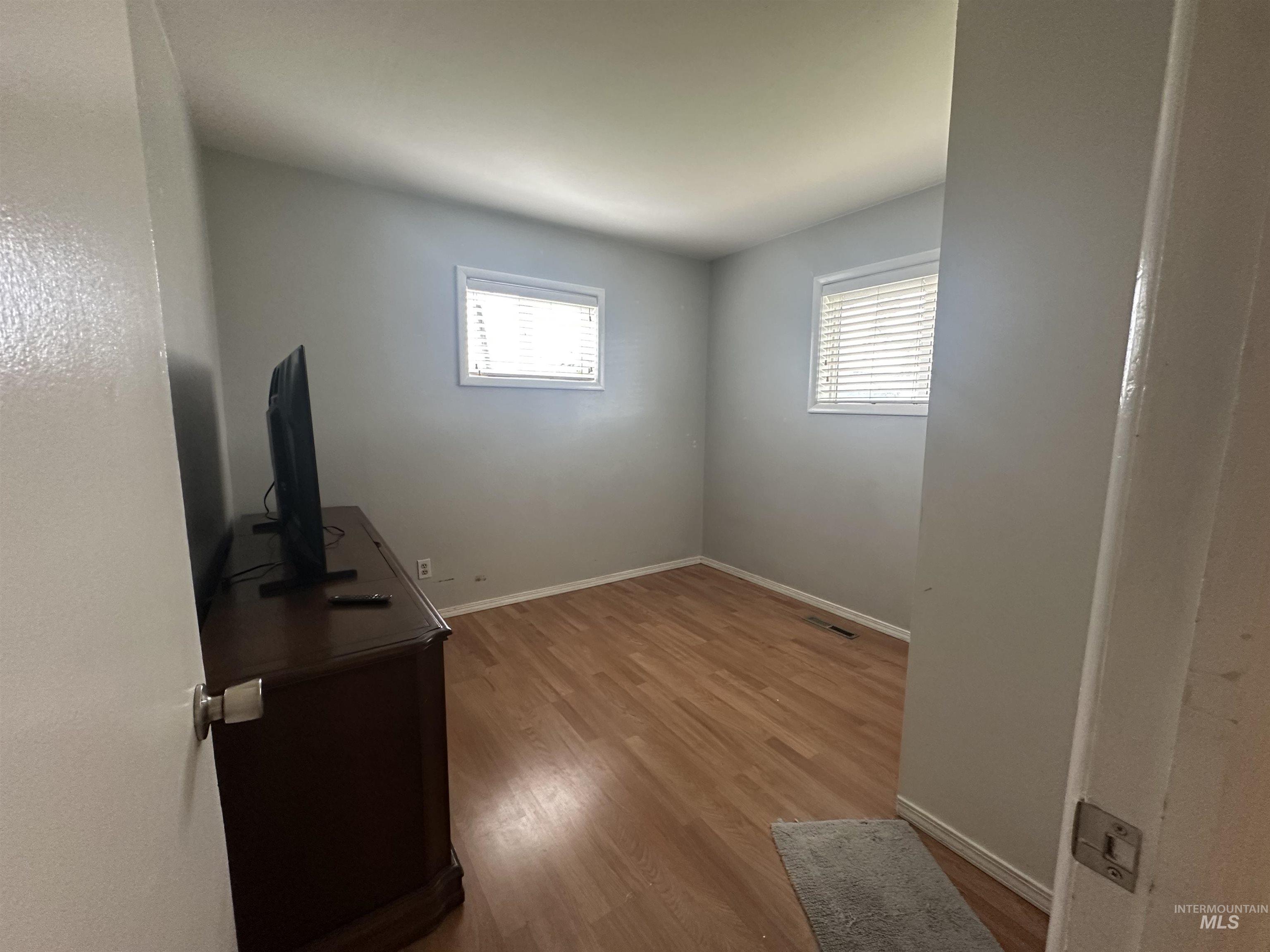 630 Preston Avenue, Unit C Lewiston, ID 83501 - Photo 9 of 10 Interior room featuring wood-finish flooring, two windows with blinds, and light-toned wall paint