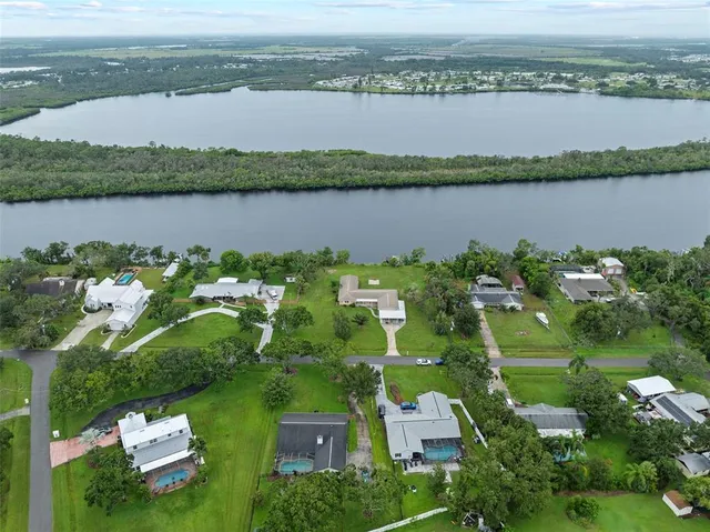 an aerial view of a residential houses with outdoor space and trees all around