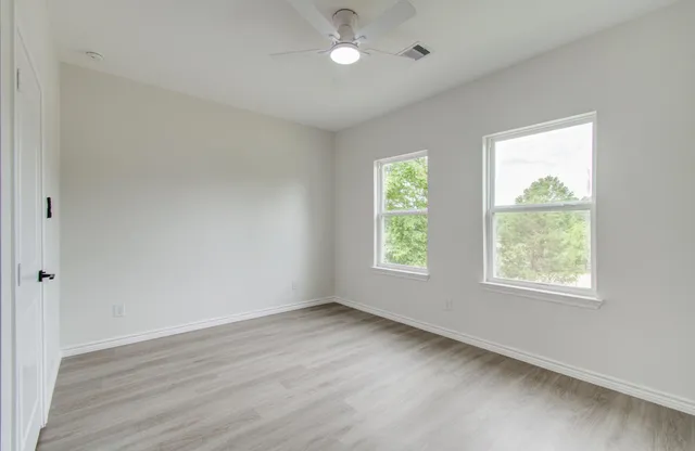 an empty room with wooden floor and windows