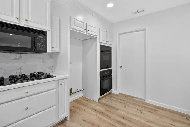 a kitchen with stainless steel appliances white cabinets and a stove top oven