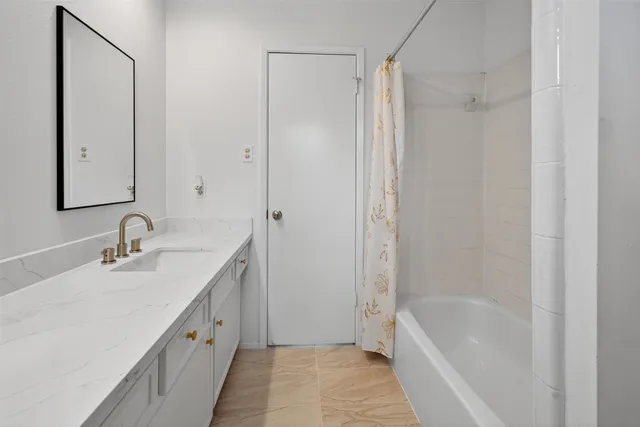 a bathroom with a granite countertop sink a mirror and a bathtub