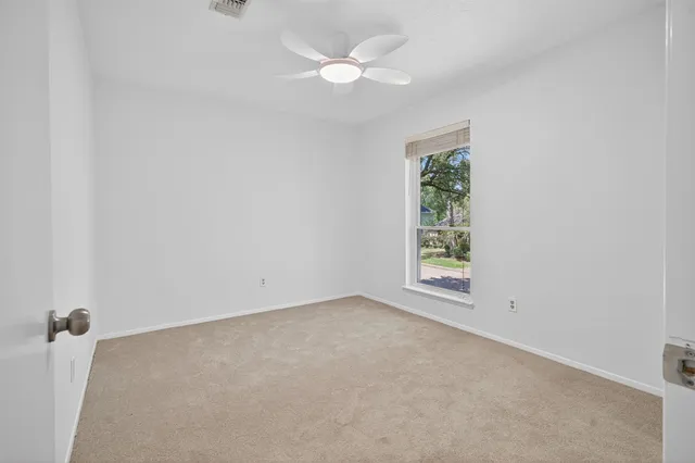 an empty room with a window and a fan