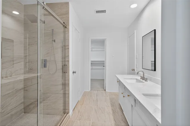 a spacious bathroom with a double vanity sink a large mirror and shower