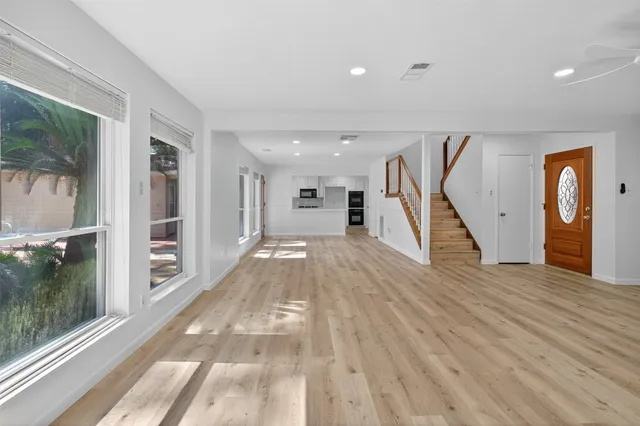 a view of a hallway with wooden floor staircase and a living room
