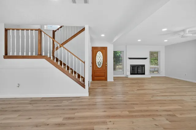 a view of an empty room with wooden floor fireplace and a window