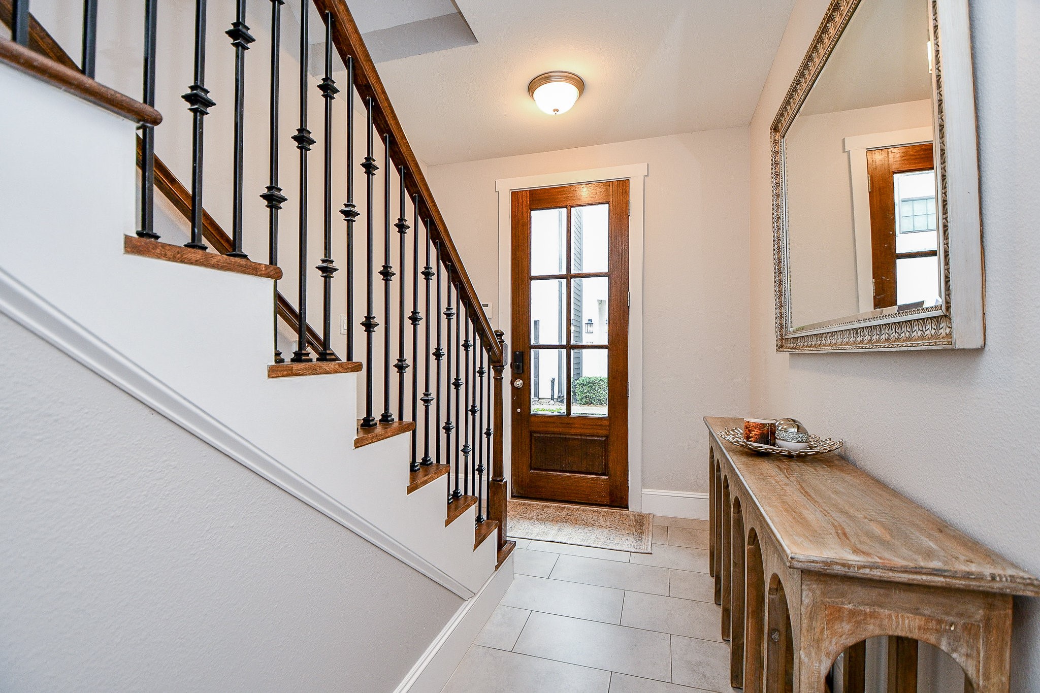 4604 Chartres Street Houston, TX 77004 - Photo 3 of 20 A warm wooden door with glass panel sidelights opens into a bright and welcoming foyer. The kind of entry that immediately feels like home. Classic iron balusters, clean white walls, and curated accents set a sophisticated tone before you even take your first step inside.