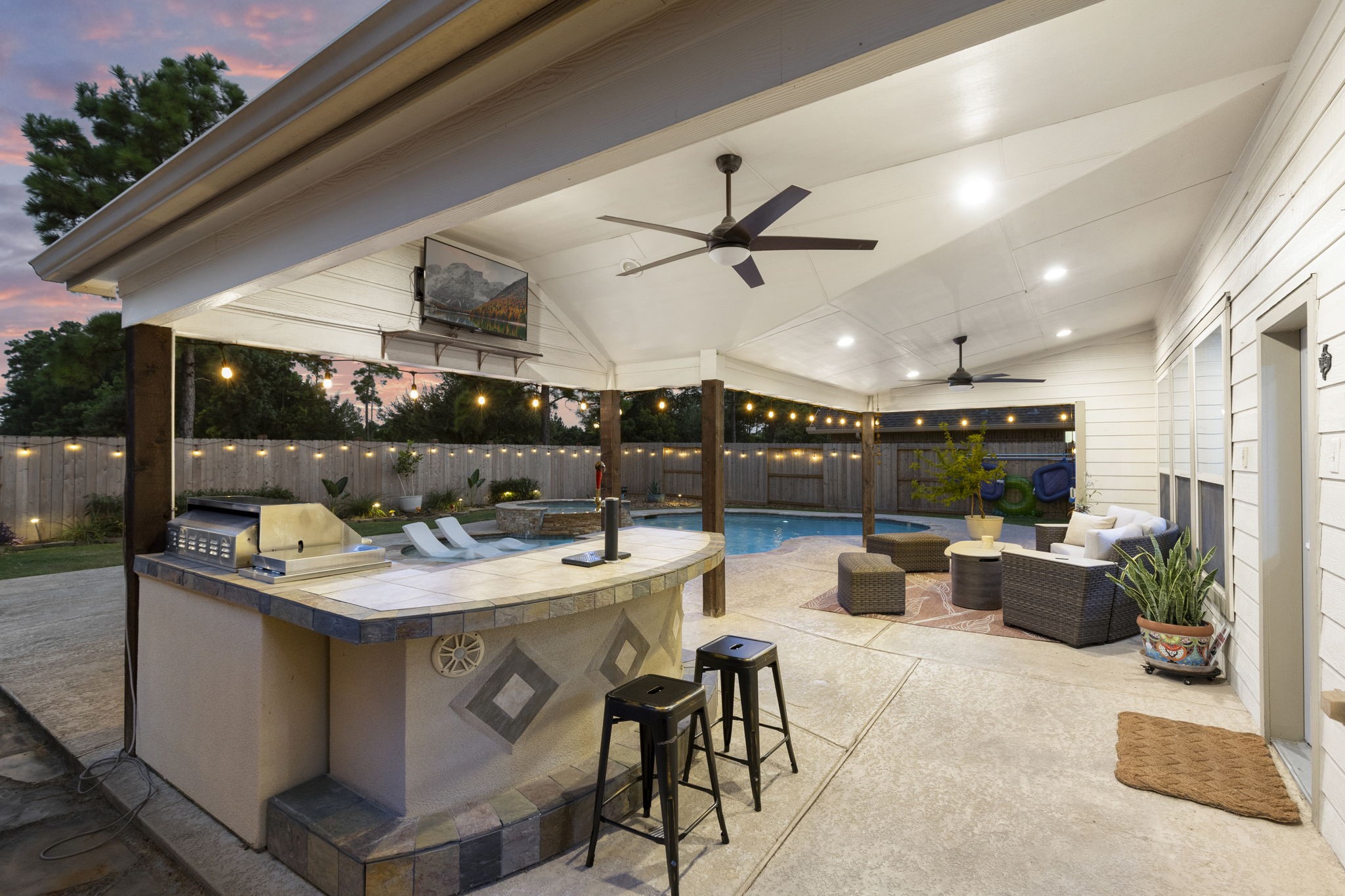 3318 Solvista High Court Spring, TX 77386 - Photo 26 of 33 Resort-style outdoor living features an expansive covered patio with a fully equipped outdoor kitchen, bar seating, multiple gathering spaces, and sparkling pool—perfect for relaxing or entertaining year-round.