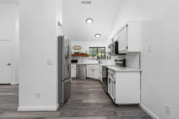 a kitchen with stainless steel appliances granite countertop white cabinets a sink and a oven