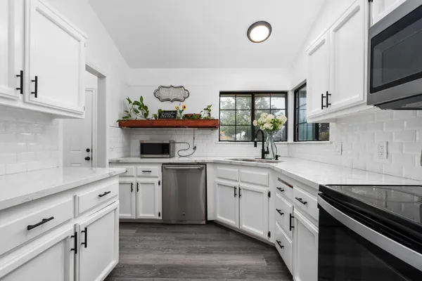 a kitchen with stainless steel appliances a stove microwave and sink
