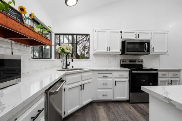 a kitchen with stainless steel appliances a stove microwave and sink