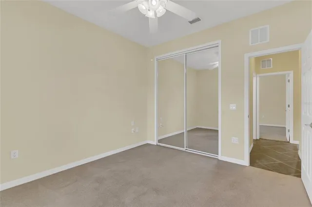 an empty room with closet and a chandelier fan