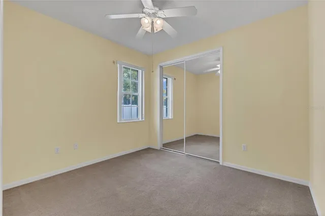 an empty room with a ceiling fan and a window