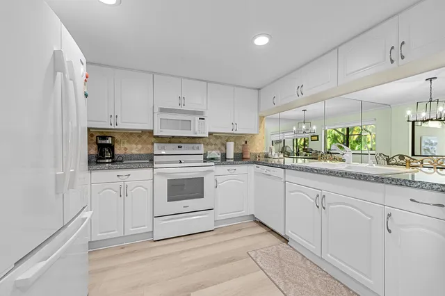 a white kitchen with granite countertop white cabinets and white appliances