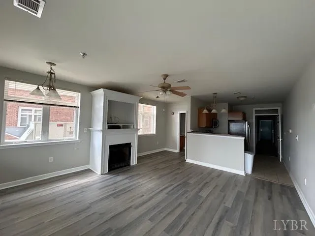 an empty room with wooden floor and a kitchen