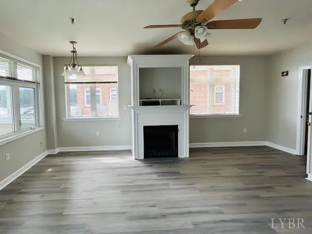 an empty room with windows fireplace and wooden floor