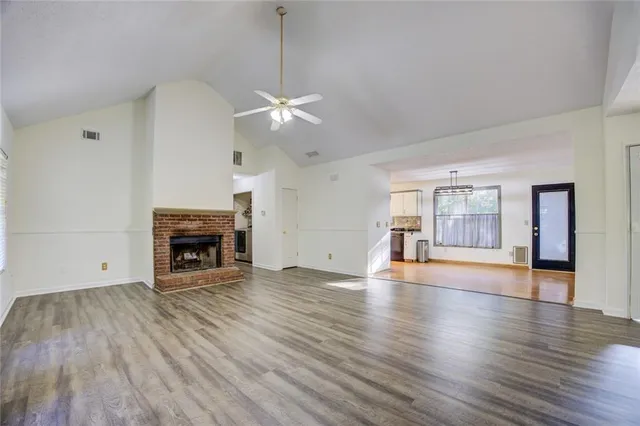 an empty room with wooden floor chandelier fan and windows