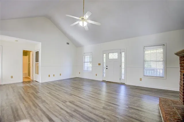 an empty room with wooden floor fireplace and windows