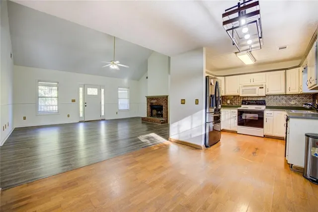 a view of a kitchen with a sink and dishwasher a refrigerator with wooden floor