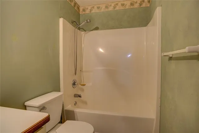 an empty room with chandelier fan and windows