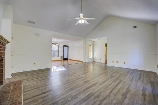 a view of an empty room with wooden floor fireplace and a window