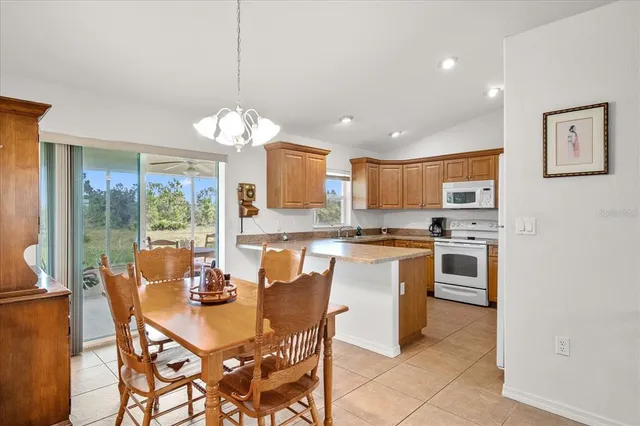 a dining room filled a chandelier a large window and a kitchen view