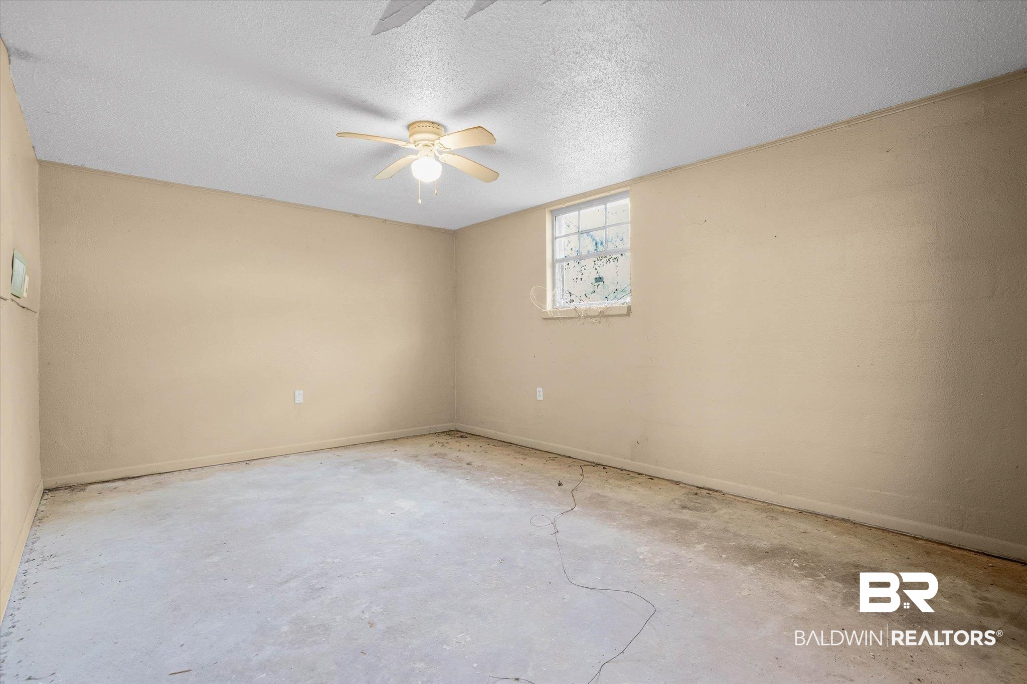 401 Frederick Avenue Fairhope, AL 36532 - Photo 13 of 36 Spacious room featuring neutral painted walls, a textured ceiling, a window for natural light, a ceiling fan with integrated lighting, and concrete flooring