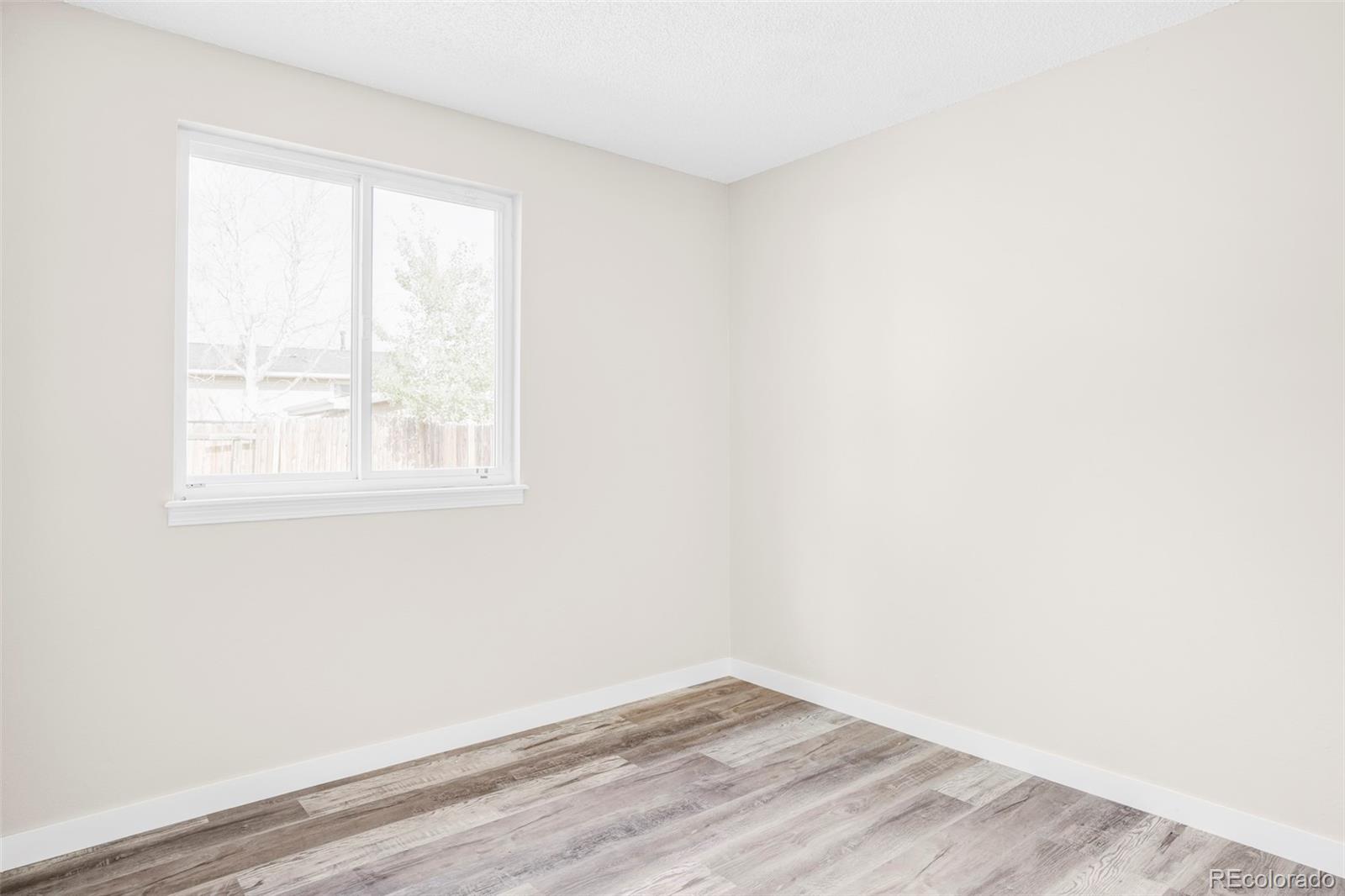 4345 Eagle Street Denver, CO 80239 - Photo 13 of 20 an empty room with wooden floor and windows