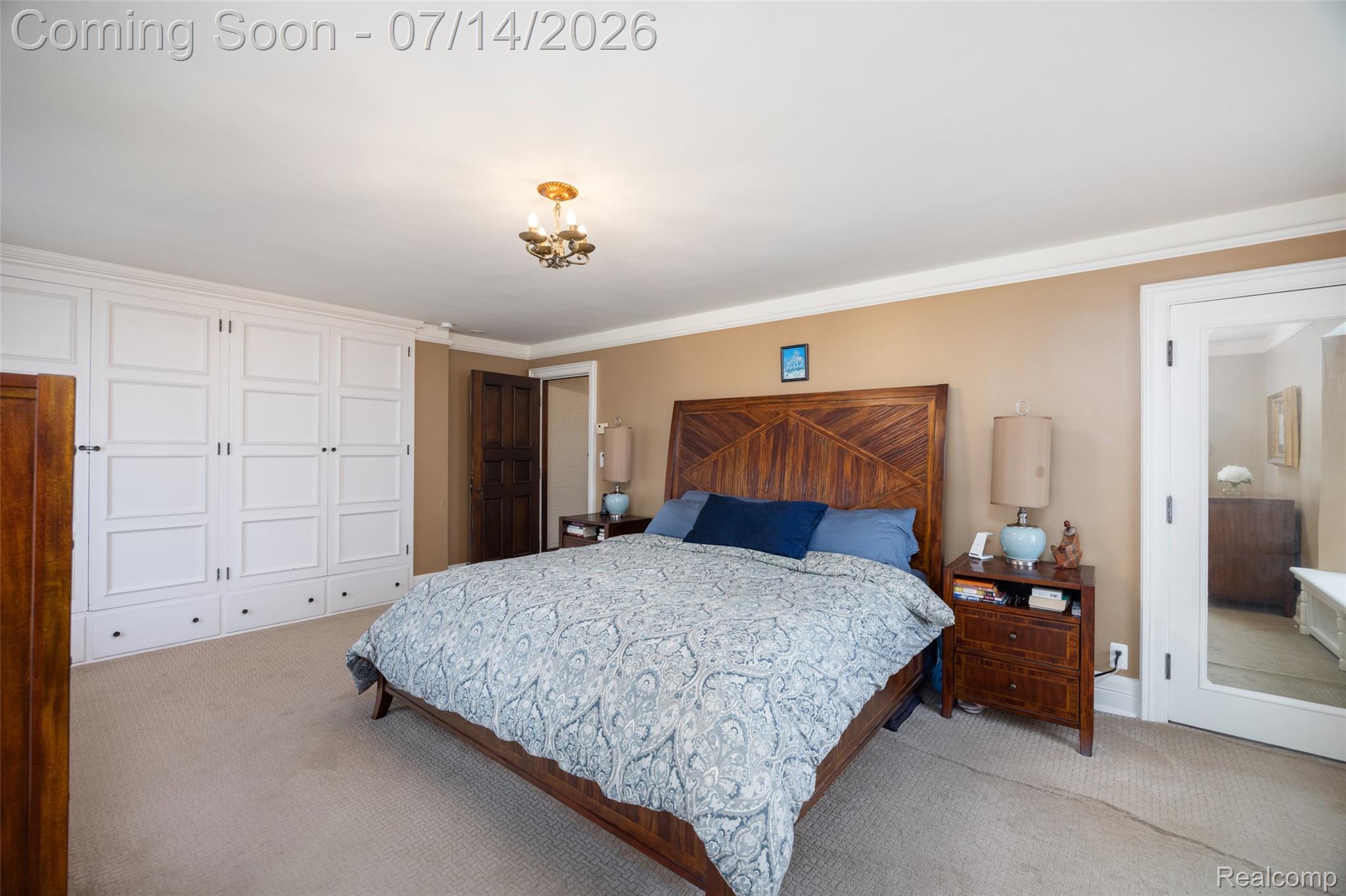 189 Cloverly Road Grosse Pointe, MI 48236 - Photo 42 of 96 Carpeted bedroom with extensive built-in white cabinetry, crown molding, a wood-finish headboard, and a brass-finish ceiling light fixture